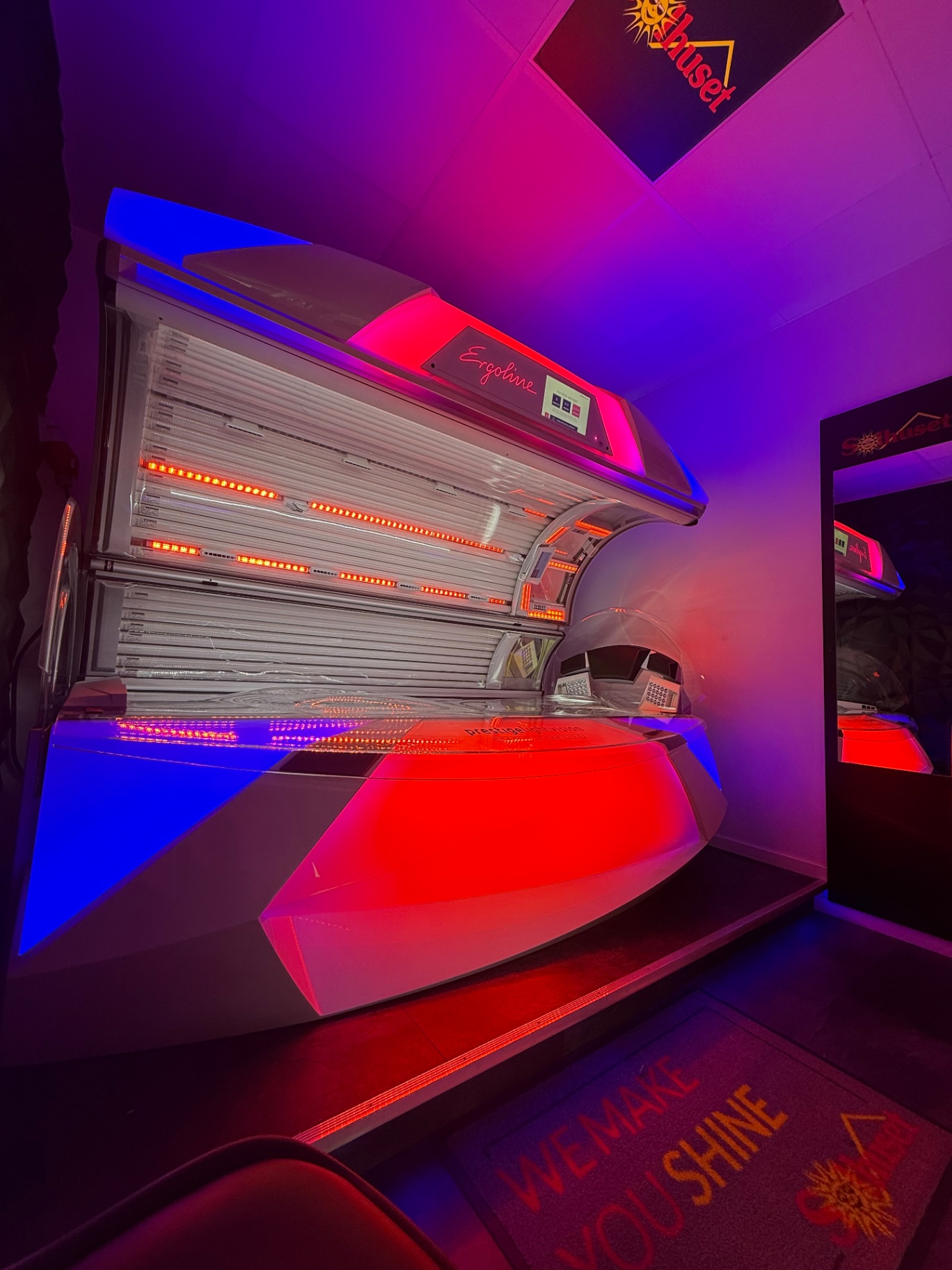 Ergoline Prestige premiumsolarium hos Solhuset i dramatisk röd och blå belysning